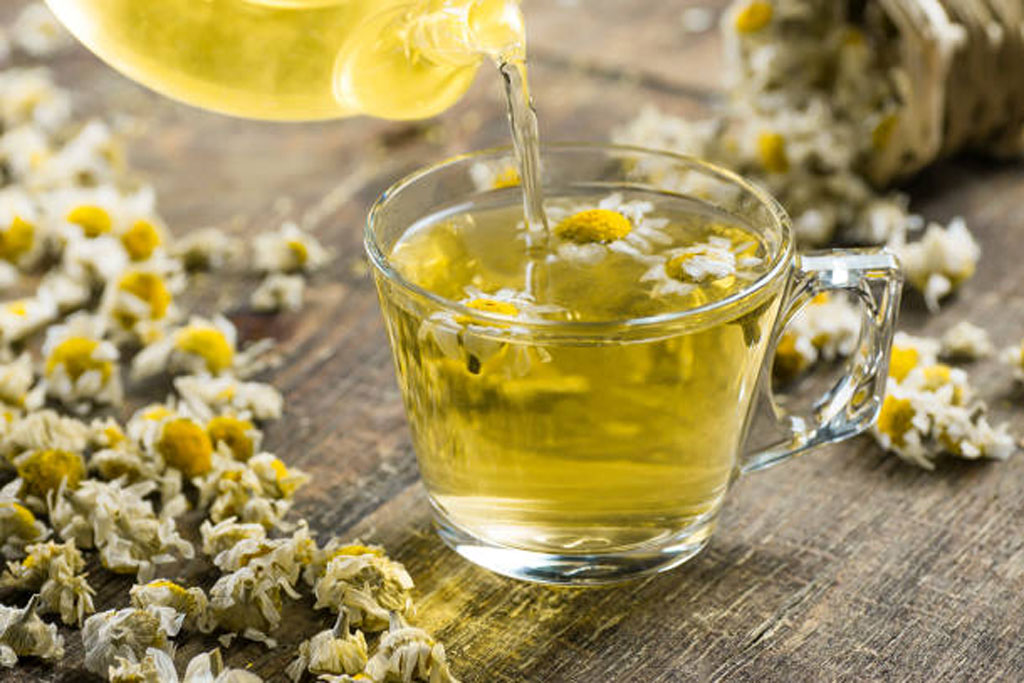 glass-cup-of-chamomile-tea-with-dry-daisy-flowers-and-teapot-
