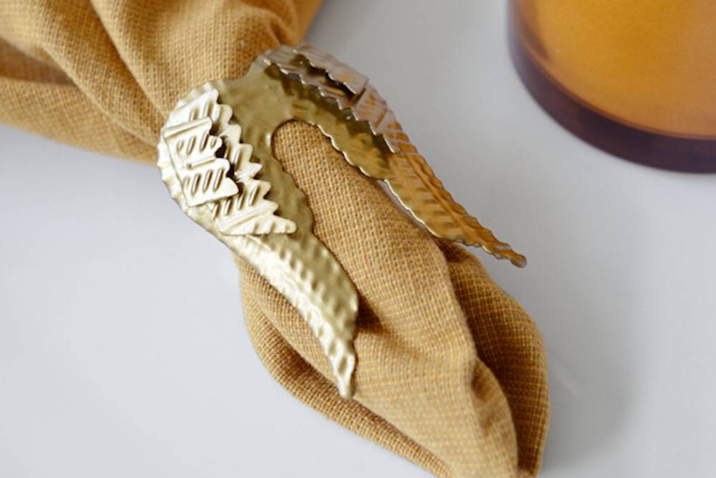 Mini gold angel wing decoration on ochre linen napkin