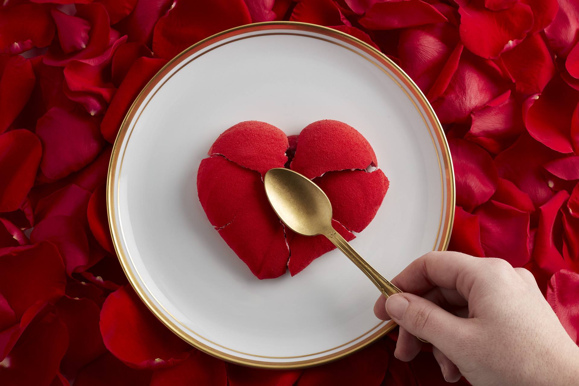 A heart shaped dessert smashed with a gold spoon