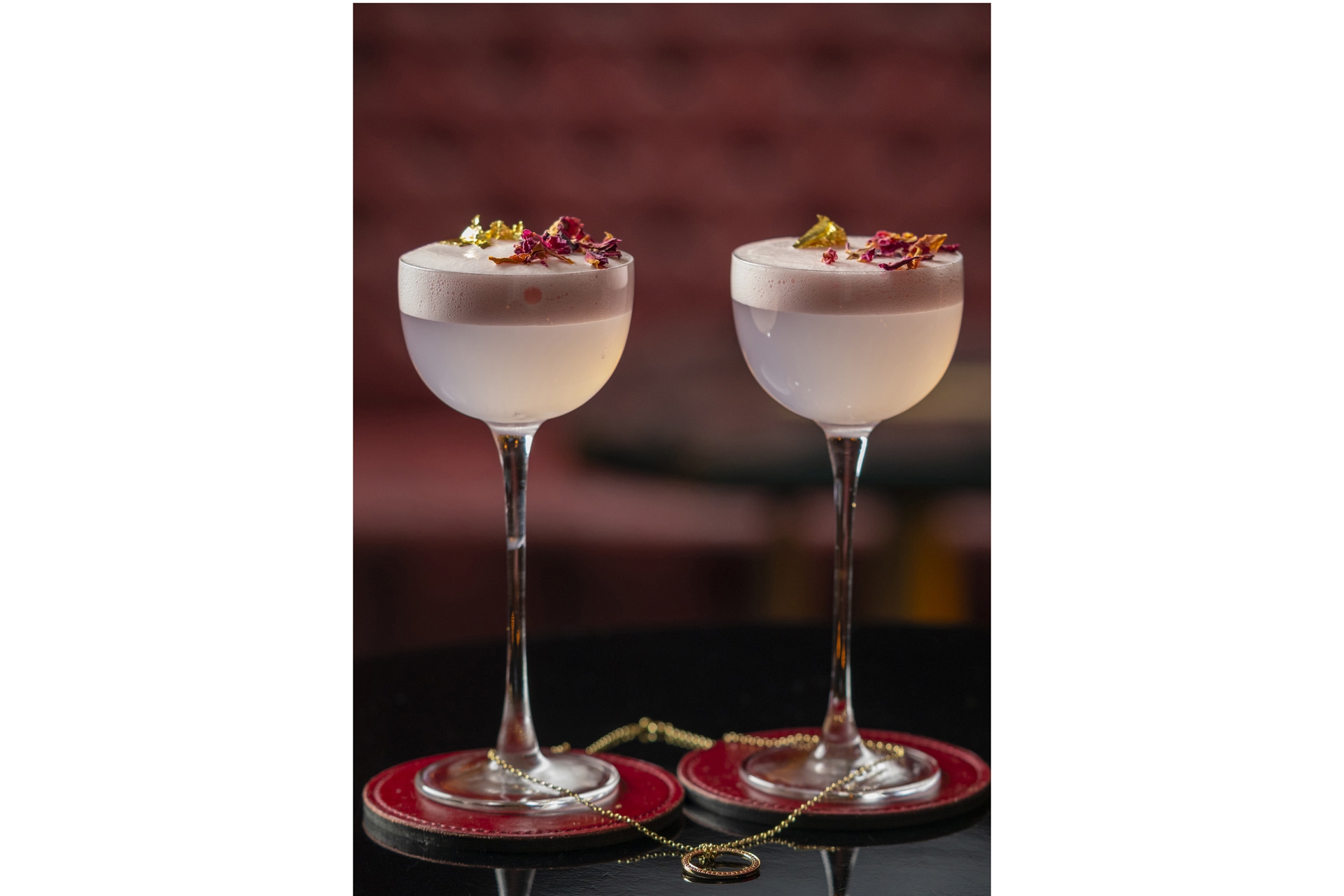 Two cocktails entwined by a pendant necklace