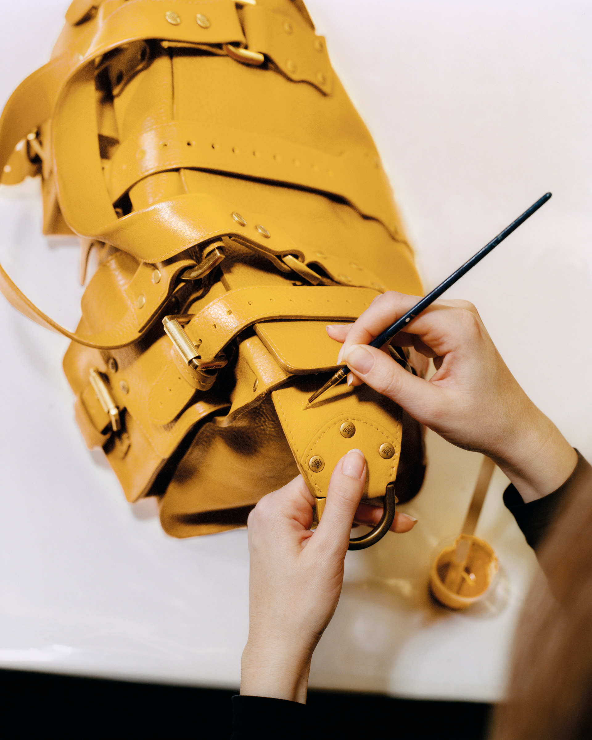 Close up of hands painting yellow leather bag