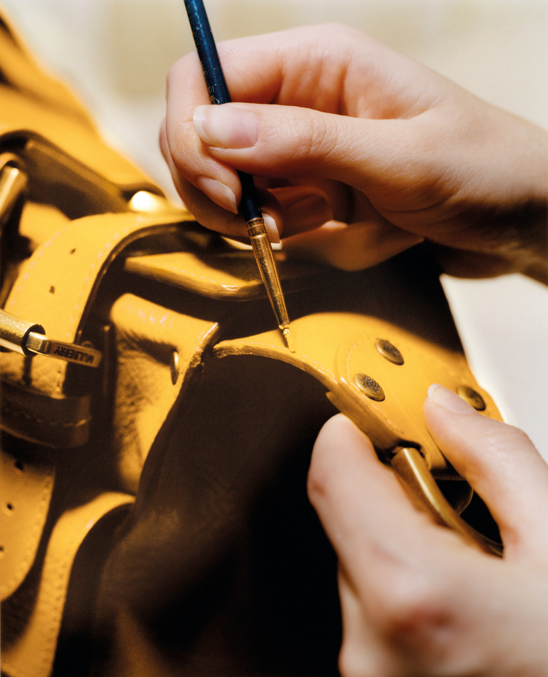Close up of hands painting yellow leather bag