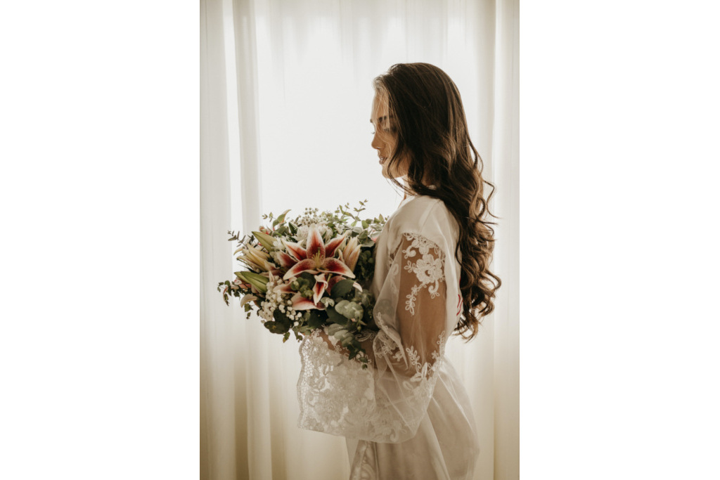 Woman holding bouquet while in white robe