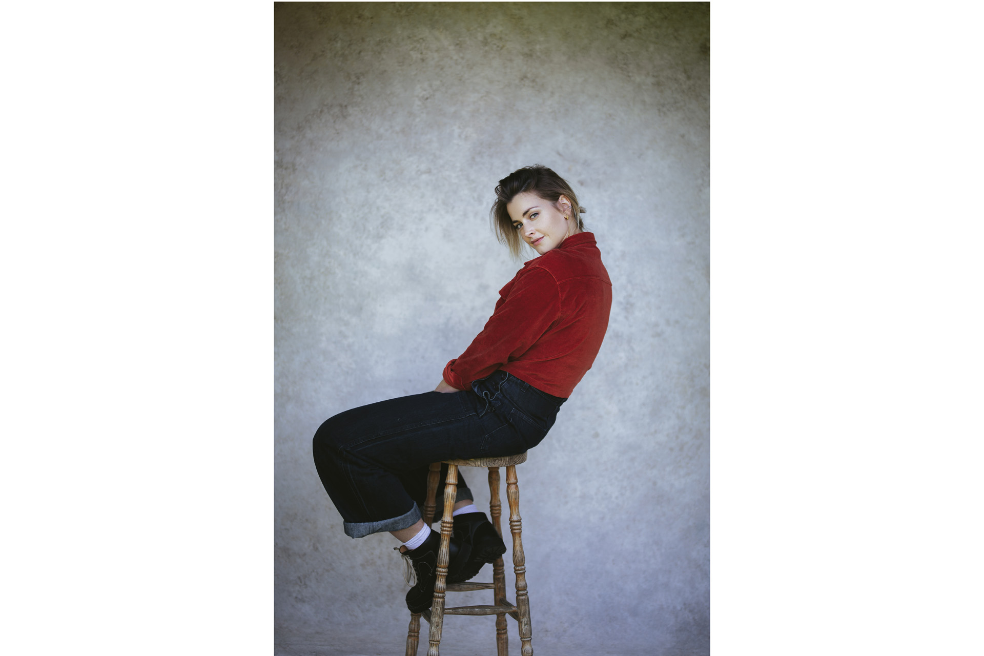 Stefanie on a stool wearing a red jumper