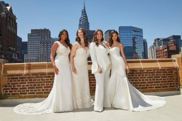 Four women in wedding outfits stood on top of building in city