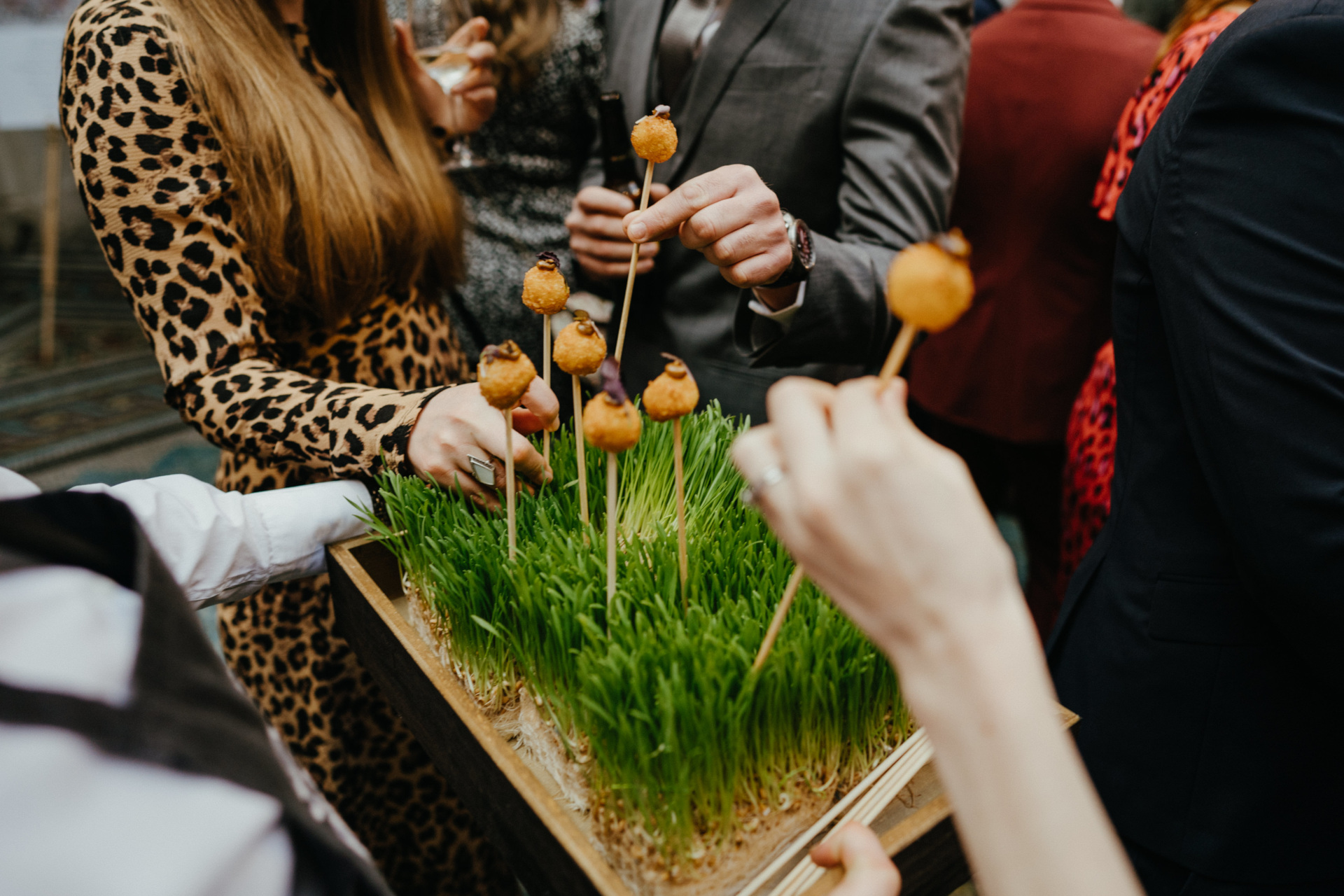 People picking out puff pastries balls from small plot of grass