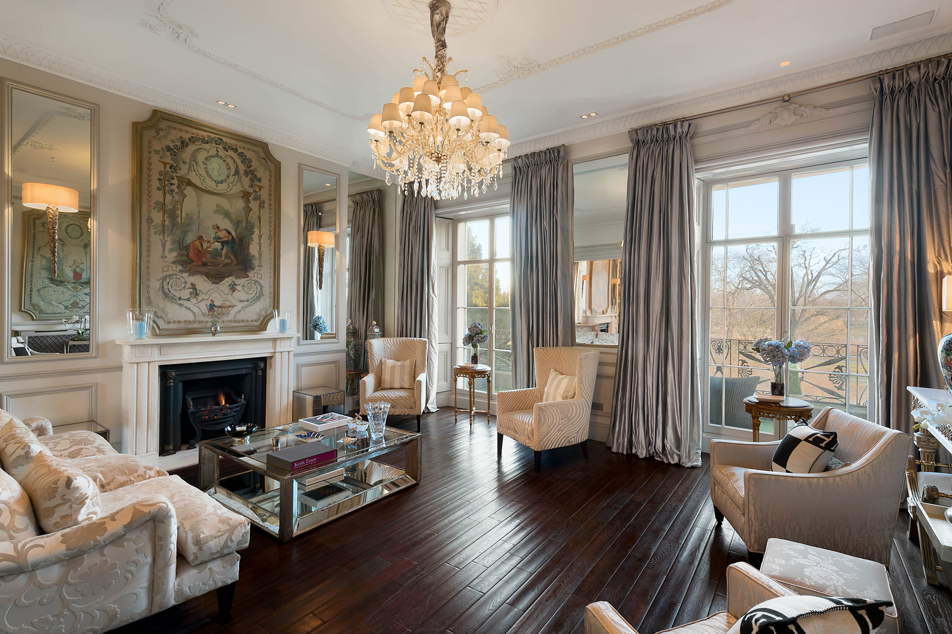 Room with high ceilings, dark wooden floorboards, cream sofas and a chandelier