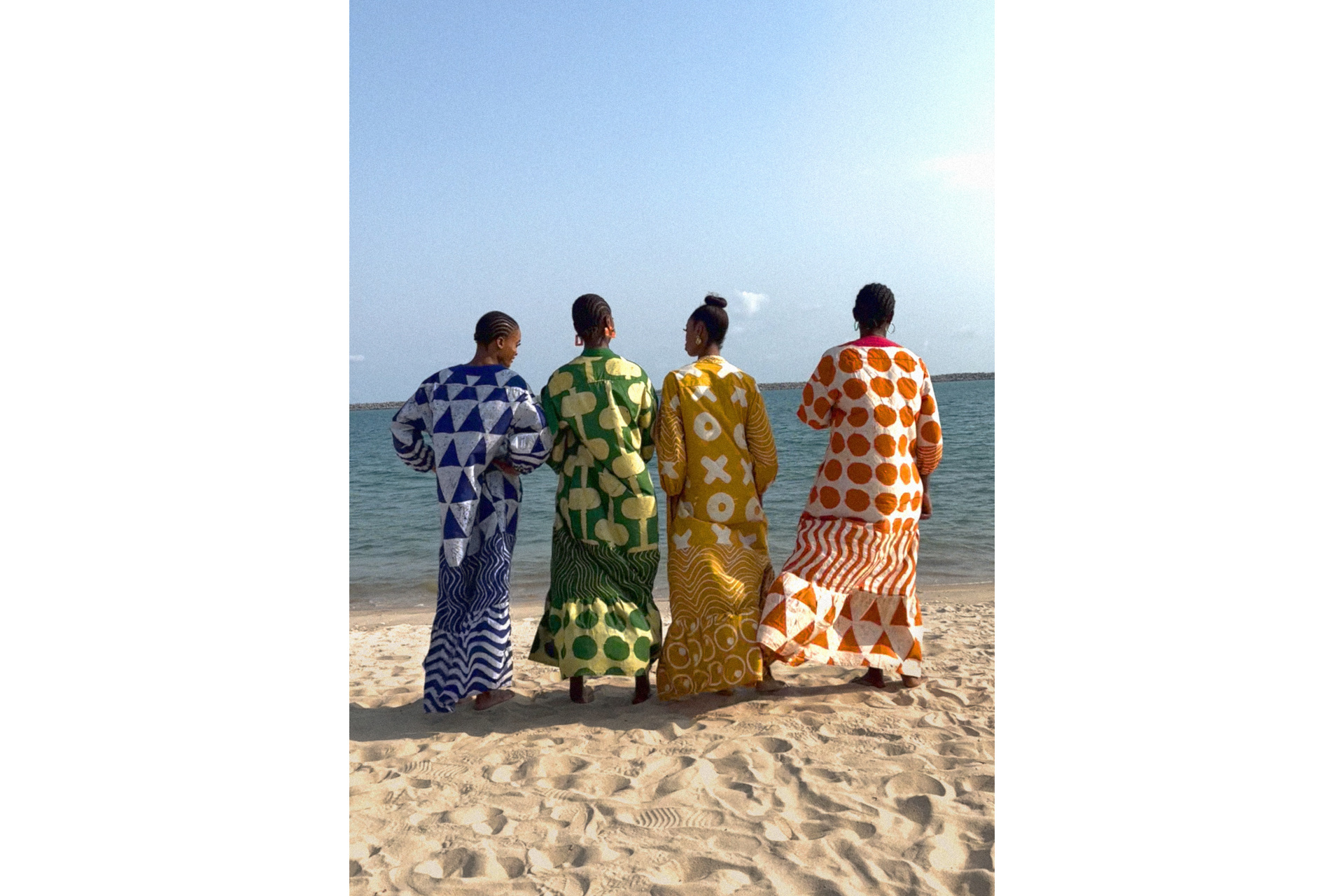 Four women on the beach in colourful print dresses