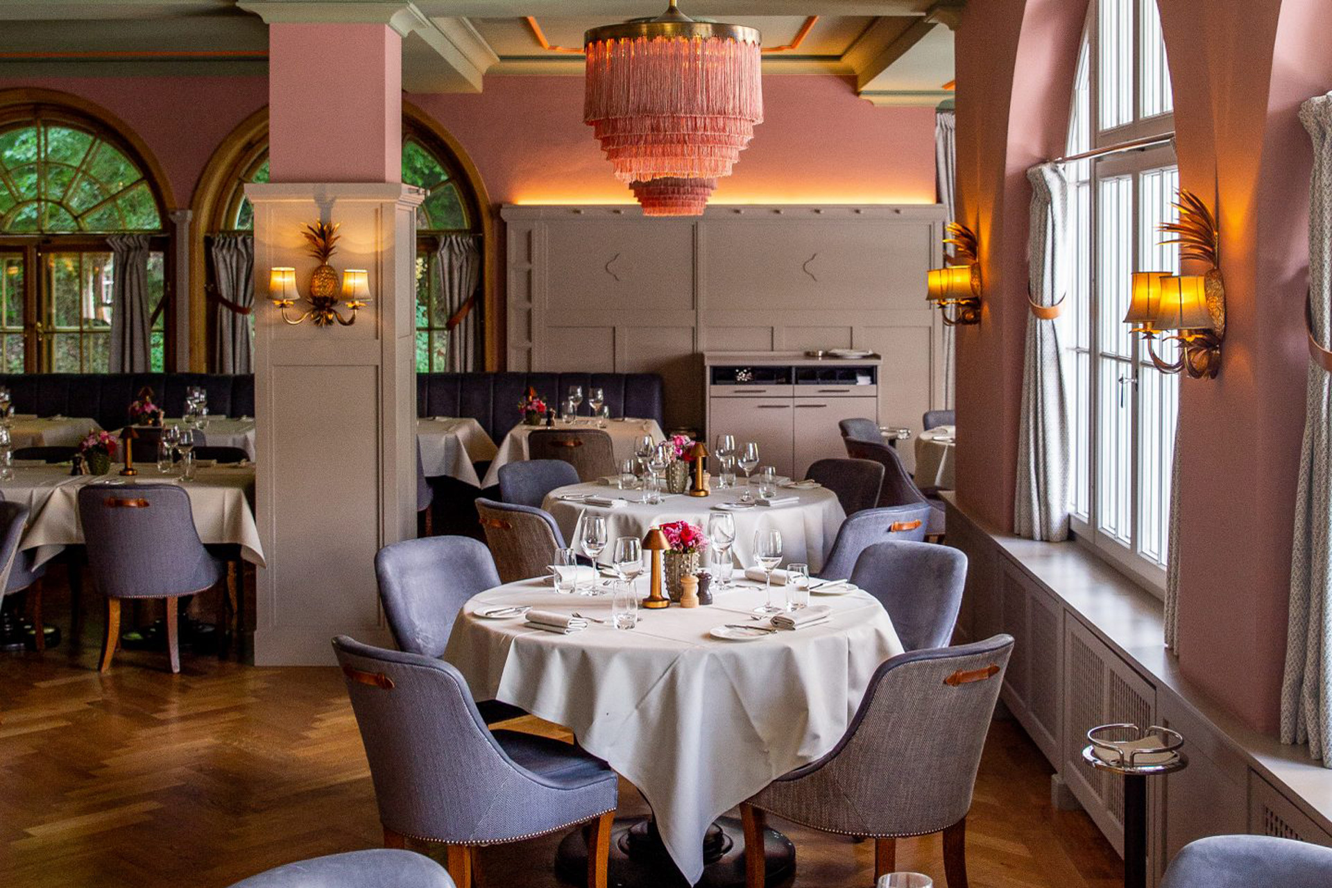 Chalet restaurant with grey chairs, white table cloths and large panelled windows looking out onto the mountain.