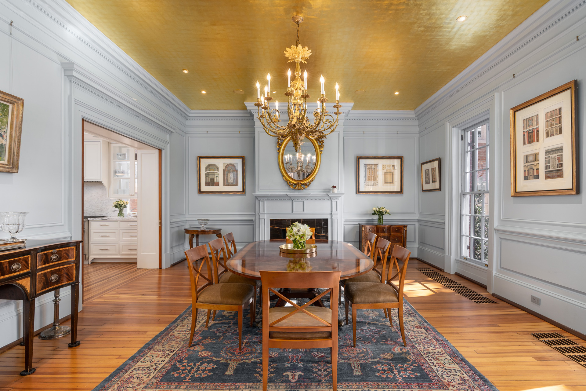 Dining room of Jackie Kennedy's former home, featuring wooden floors and furniture, chandelier, and gold ceiling