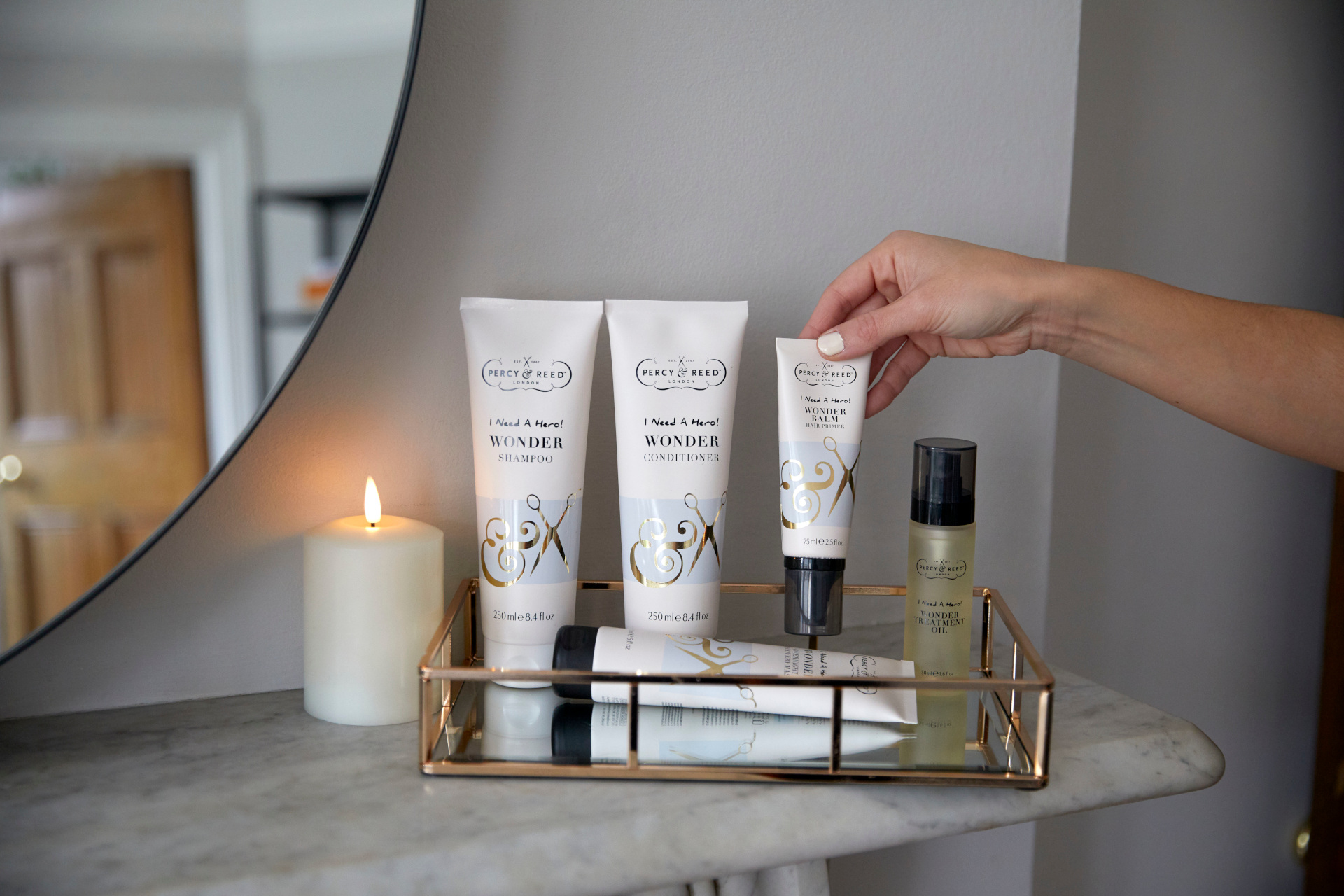 Hair care products on marble shelf next to candle