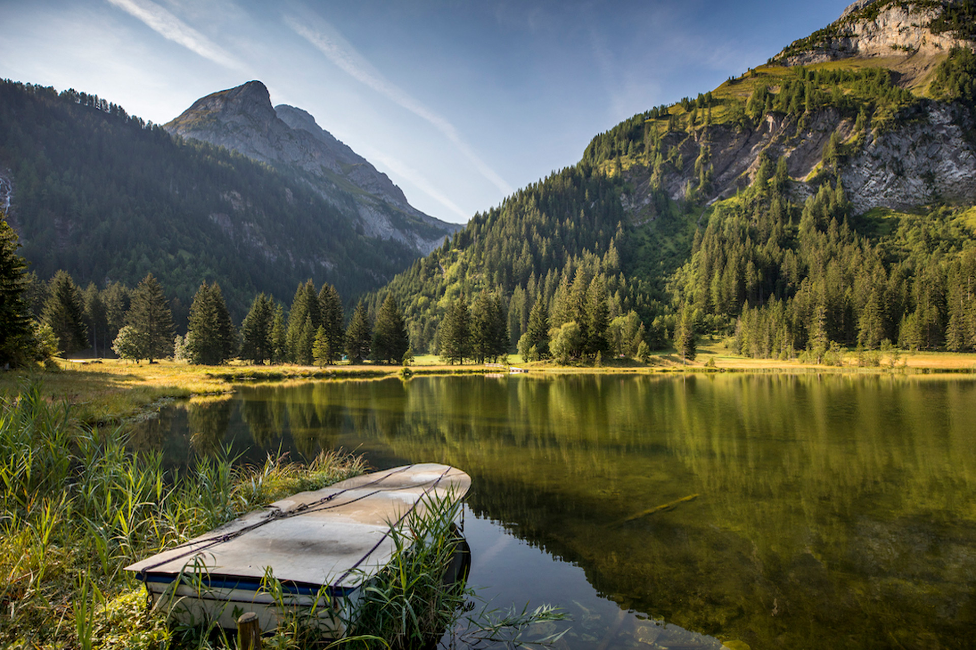 Lake with a wooden rowing boat on one side and hills beyond.