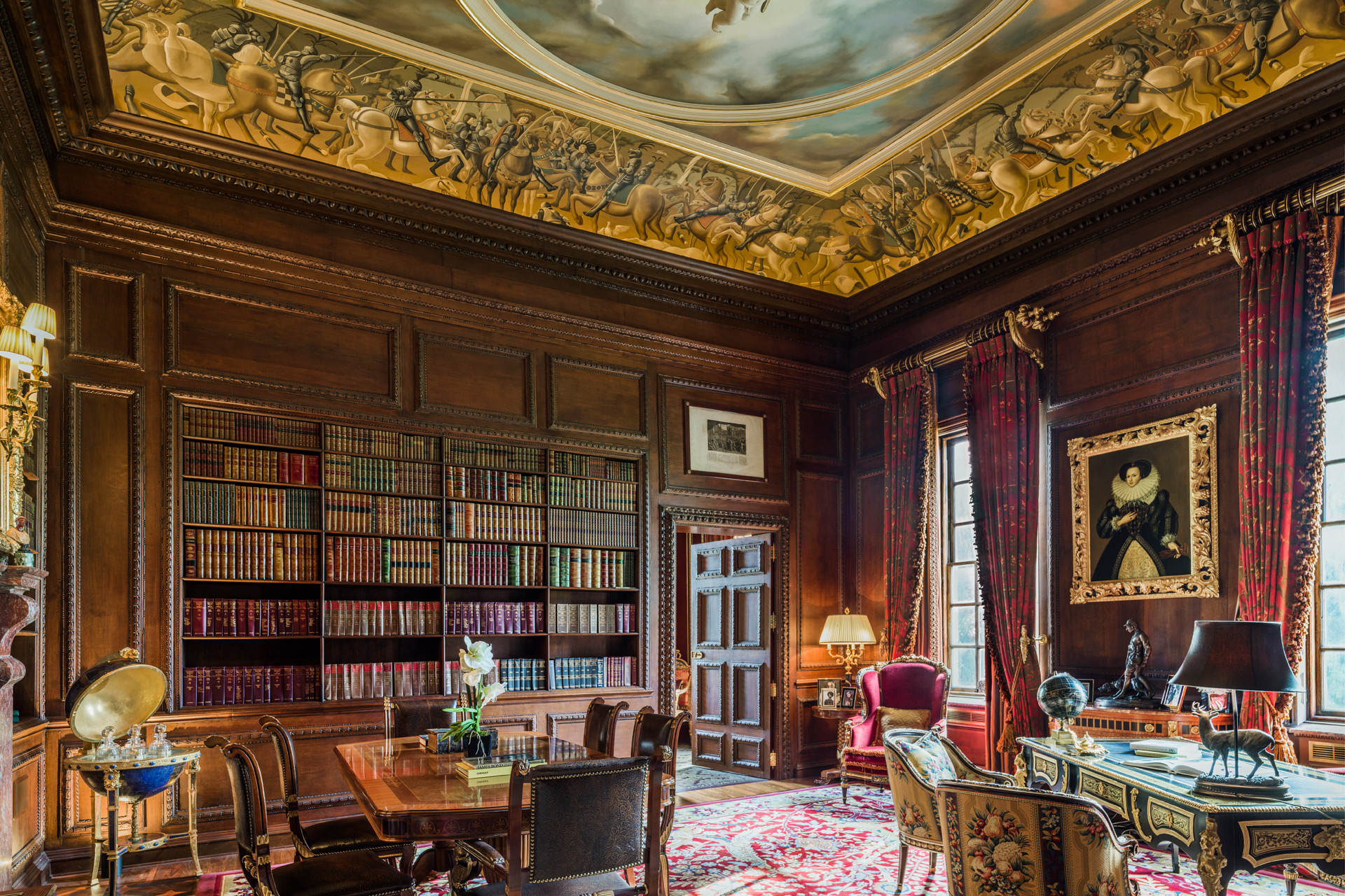 Library with wood panelling, ornate ceiling and fresco, and gilded furniture.