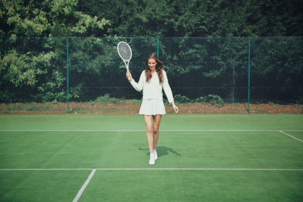Woman in white dress playing tennis