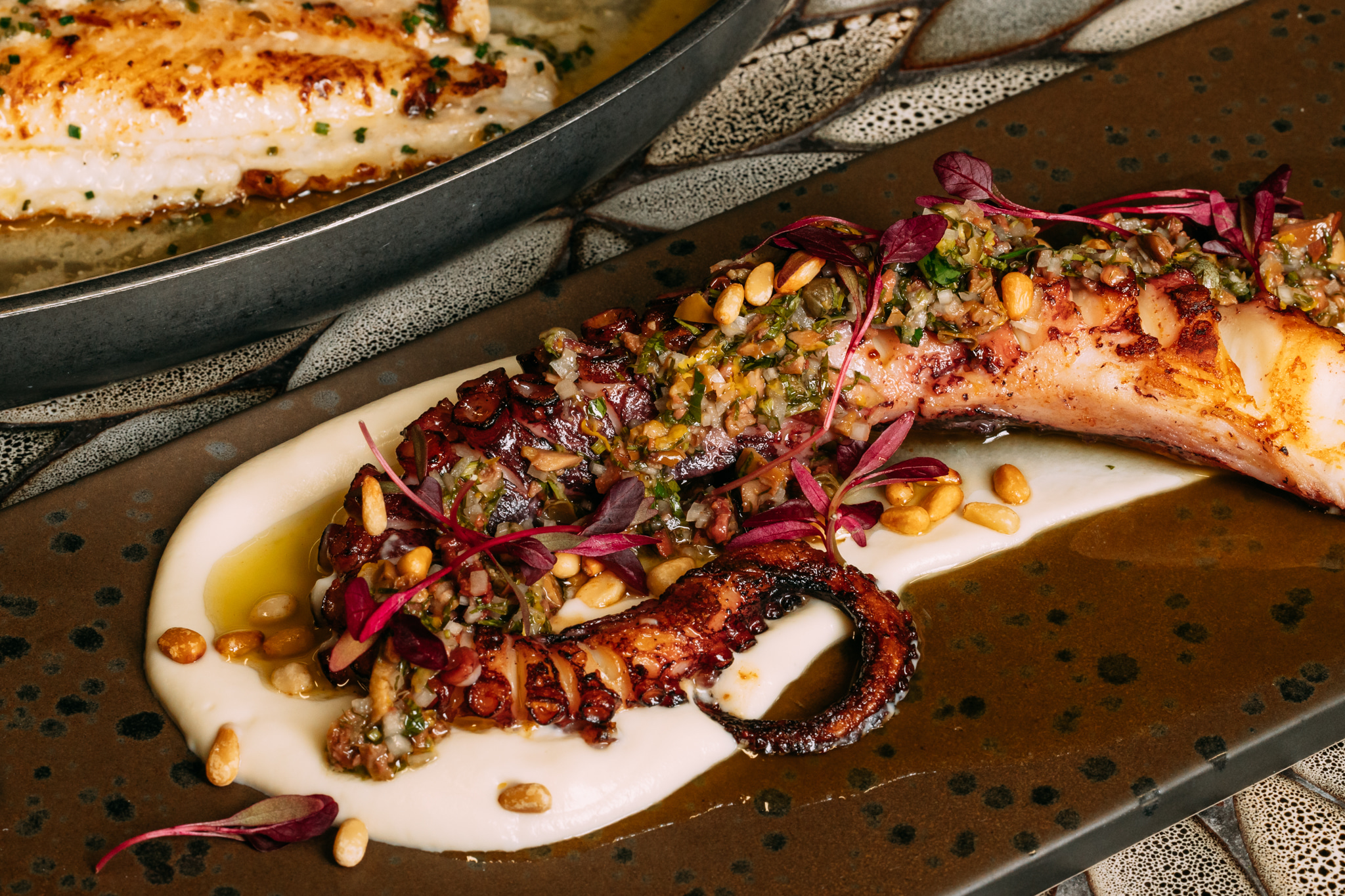 Plate of octopus topped with vegetables from Riviera restaurant.