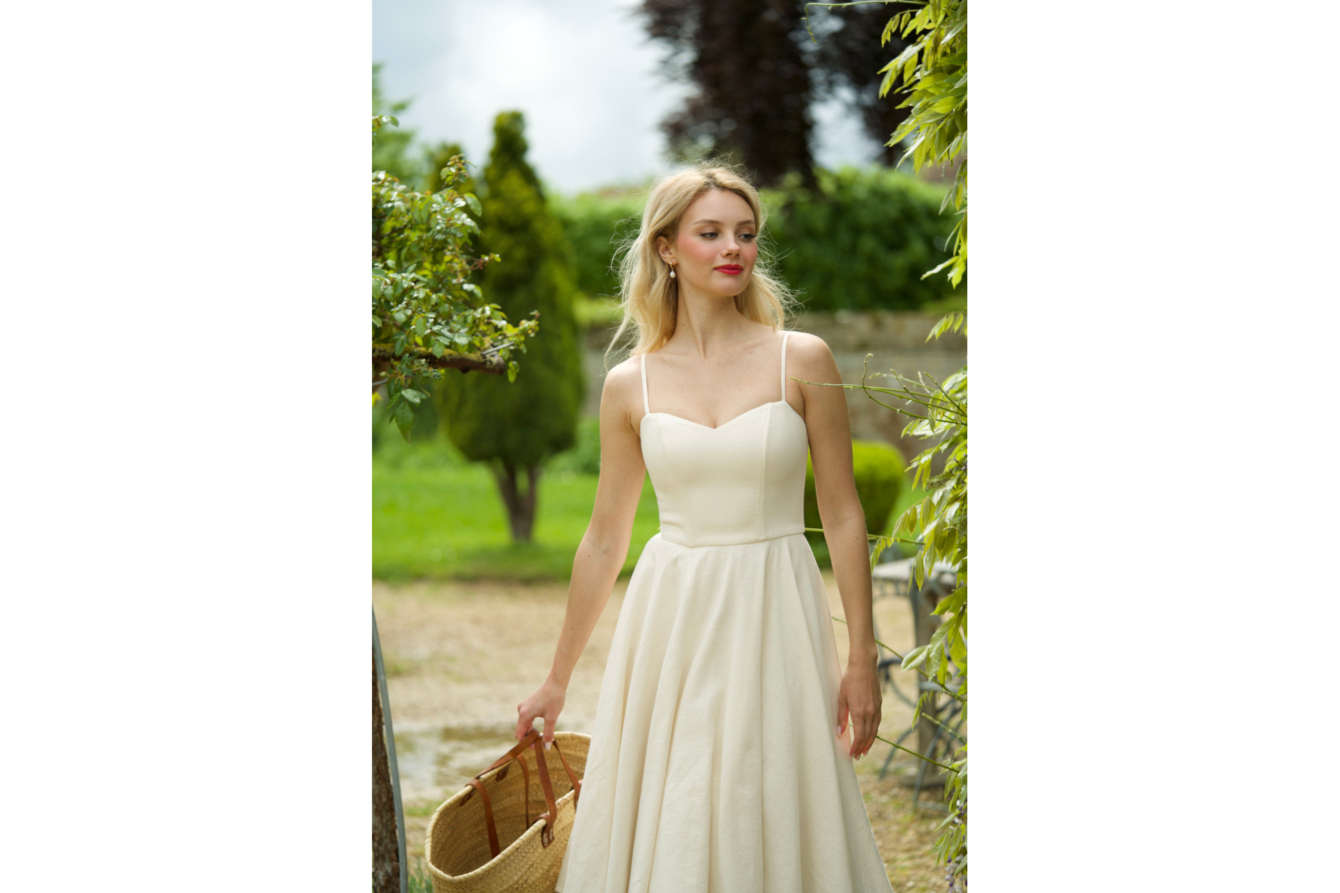 Woman in white dress holding basket in garden