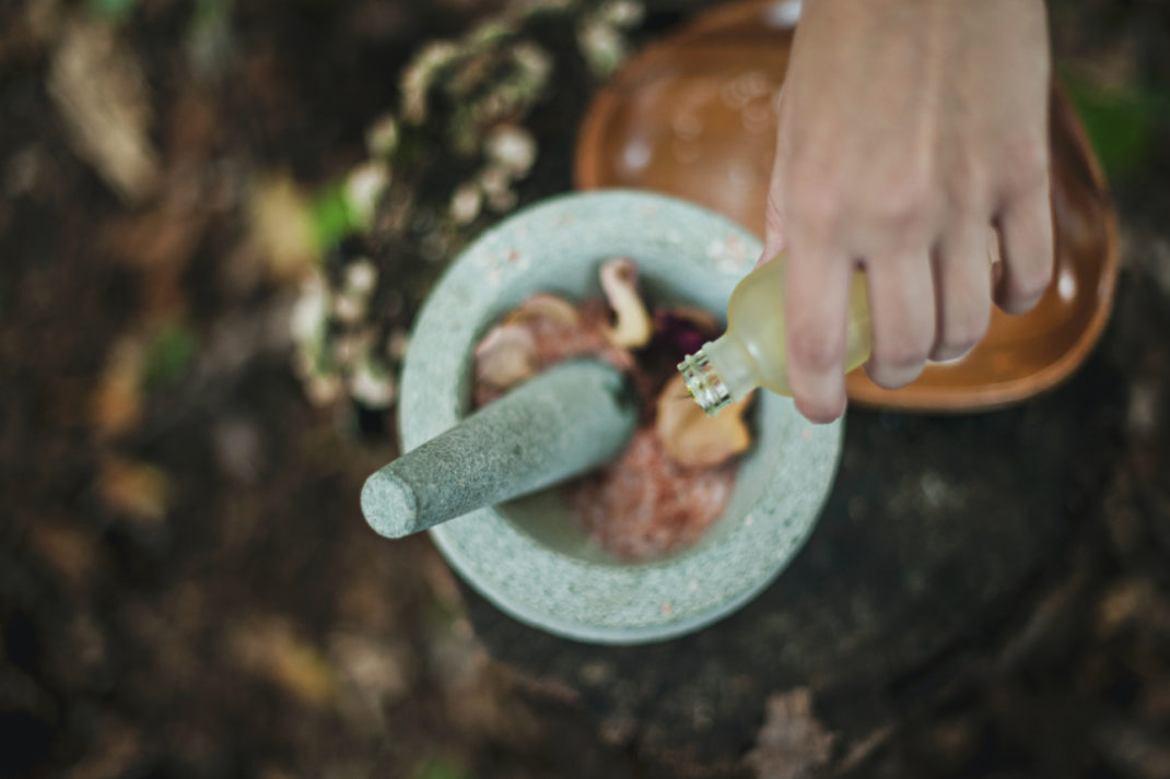Hand drizzling oil into mortar and pestle