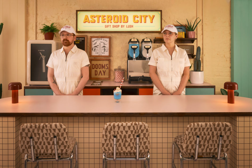 People stood behind Wes Anderson style bar