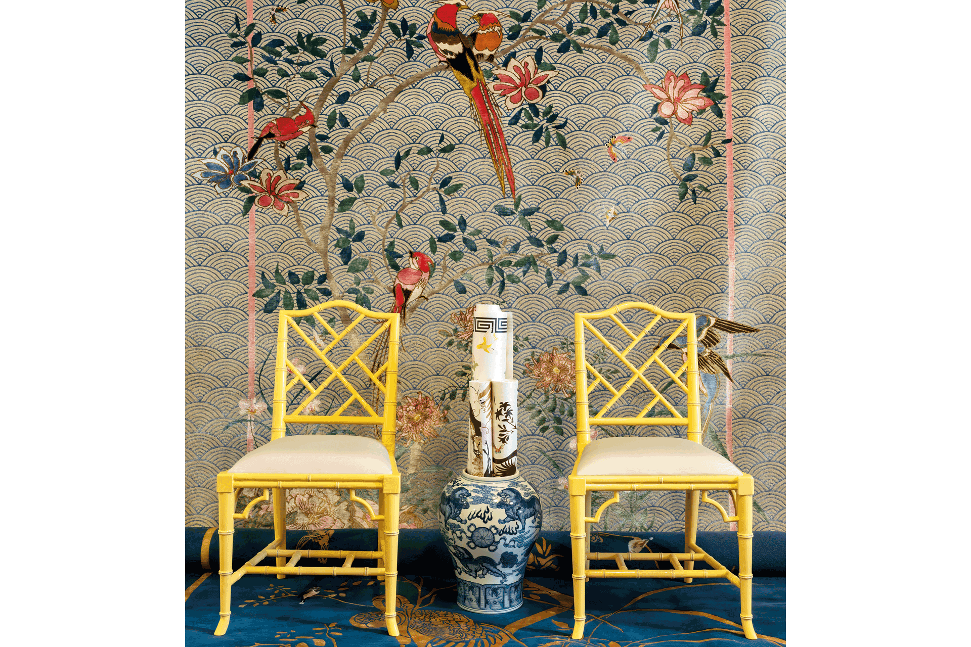 Yellow dining chairs on a blue rug with a tapestry behind