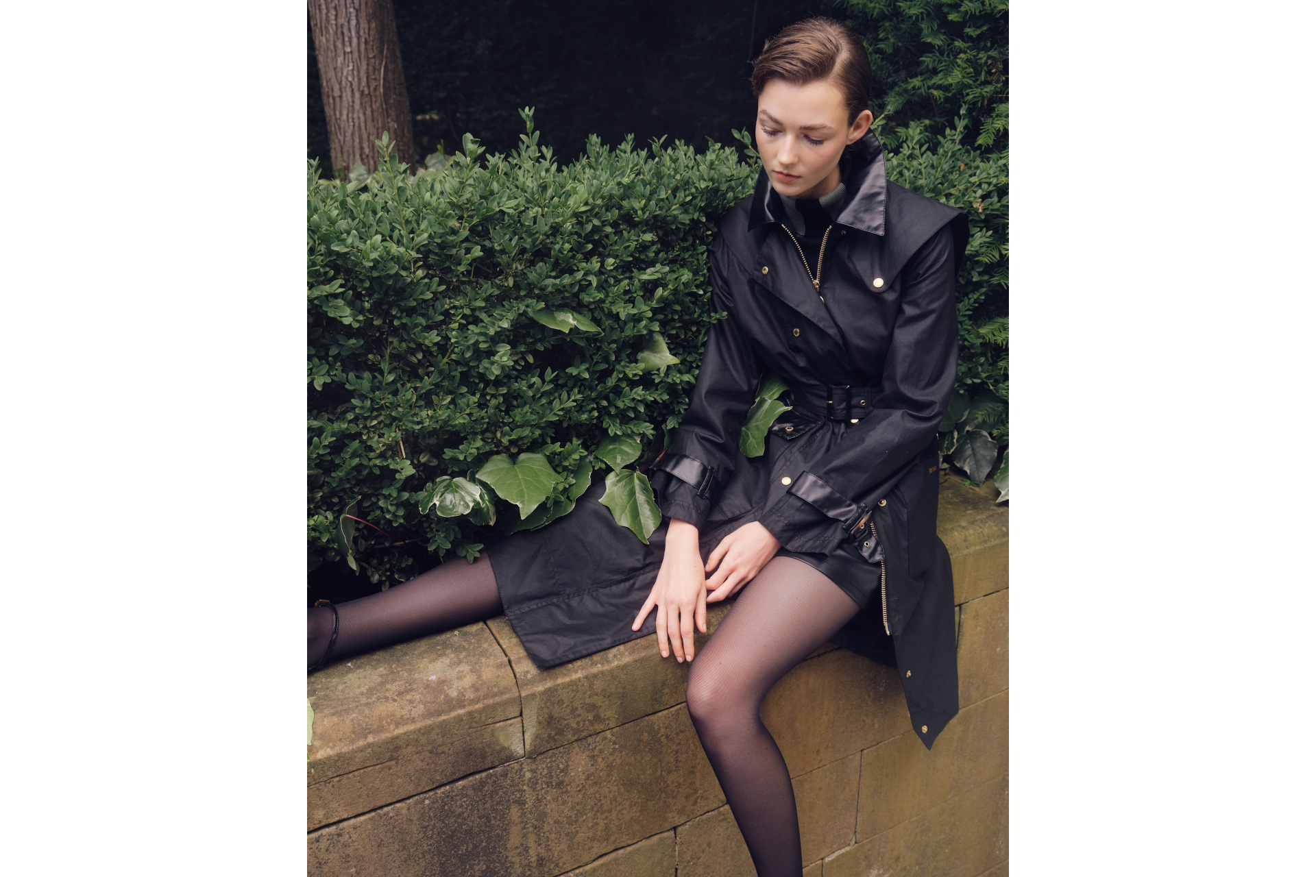 Woman in black coat sat on wall