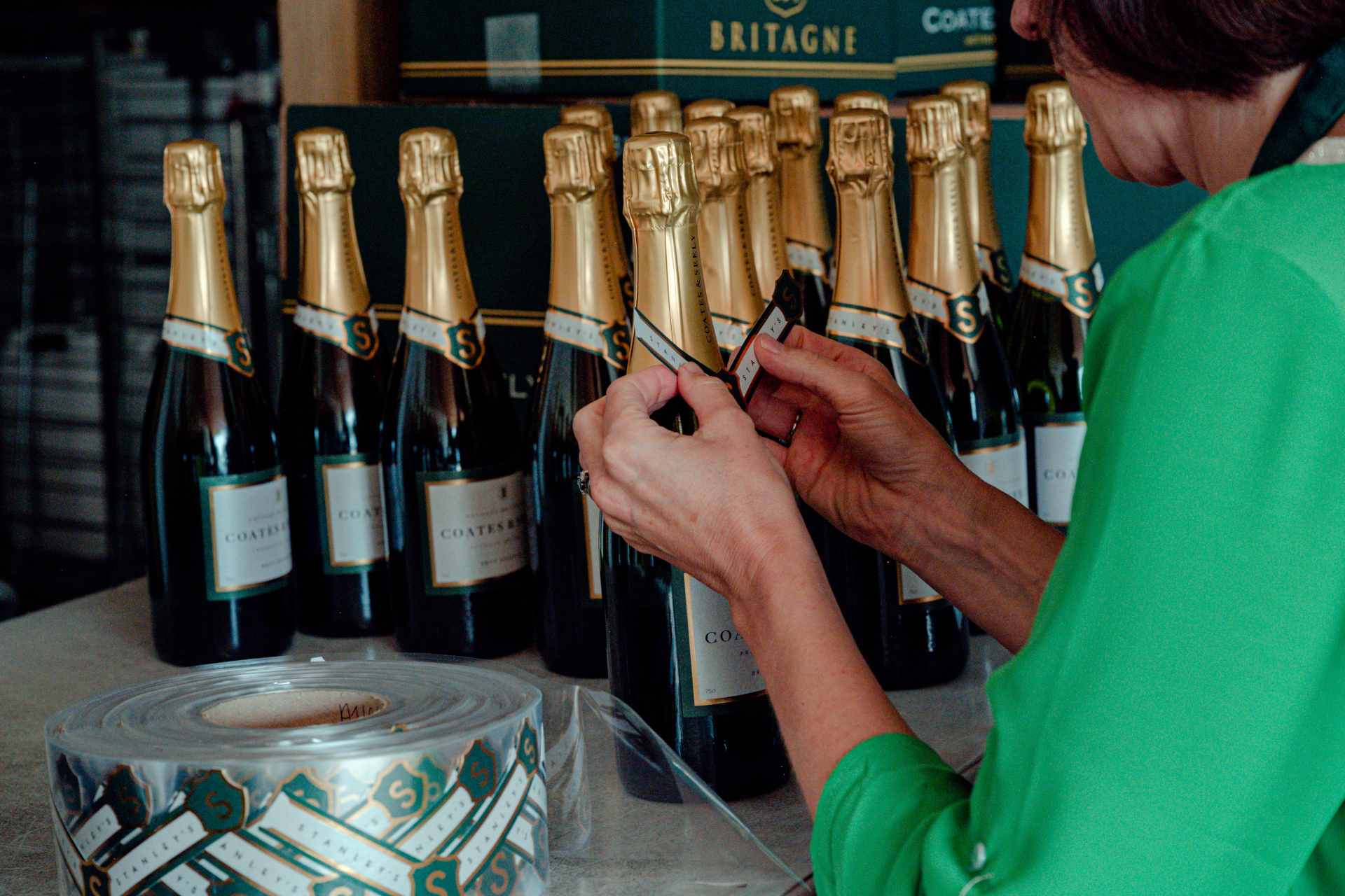 Person tying ribbon on bottle of fizz